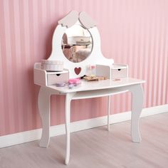 a white vanity table with drawers and a mirror on the wall next to a pink striped wall