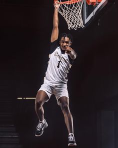 a basketball player dunking the ball into the hoop with his hands in the air