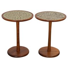 two tables made out of wood and glass with circular designs on the top, each side