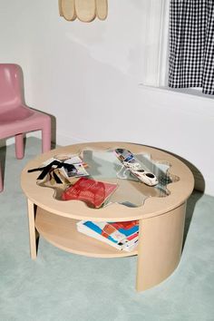 a wooden table with magazines on it in a room next to a pink plastic chair