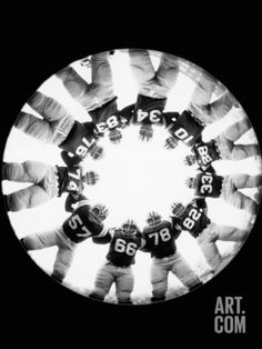 a group of people standing in a circle with numbers on their shirts and hands around them