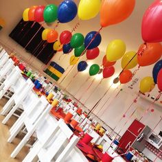 many balloons are floating in the air above tables and chairs at a birthday party or celebration