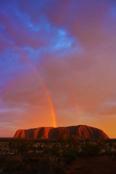 two rainbows are seen in the sky above aye rock, ulurura national park