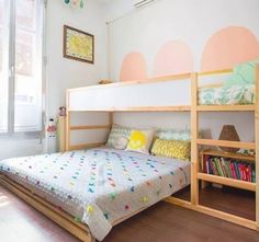 a bunk bed sitting in the middle of a bedroom next to a book shelf filled with books