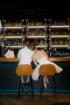 two people sitting at a bar with their backs to each other