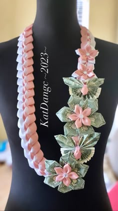 a necklace made out of money with pink flowers on the front and green leaves on the back