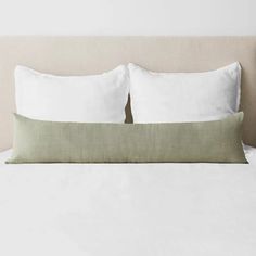 a bed with two white pillows and one green pillow on it's headboard