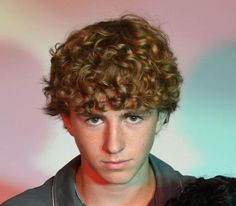 a young man with curly hair holding a black dog