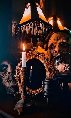 a table topped with a mirror next to a skull and a lit candle on top of it