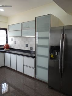 a kitchen with white cabinets and black counter tops, stainless steel refrigerator and dishwasher