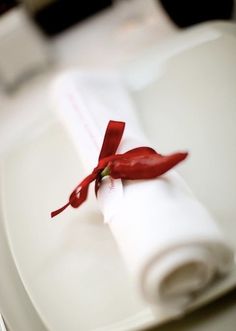 a white plate topped with a napkin and red ribbon tied to it's edge