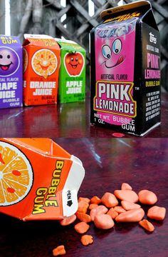 an assortment of pink lemonade candy on a table next to two cartons of orange juice