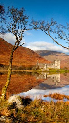 a castle sitting on top of a lake surrounded by mountains