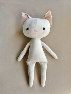 a white cat doll laying on top of a brown table next to it's head