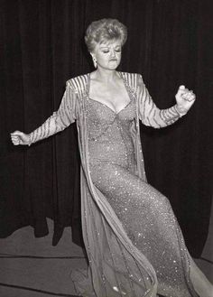 an old photo of a woman in a dress on stage with her hands out to the side