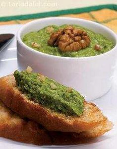 a white plate topped with two pieces of bread and a bowl of green pesto