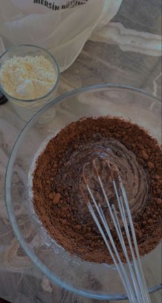 the ingredients are being mixed together to make a chocolate cake in a glass bowl with whisks