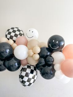 a bunch of balloons that are in the shape of smiley faces and checkered balls