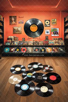 a room filled with lots of records on top of hard wood flooring next to an orange wall