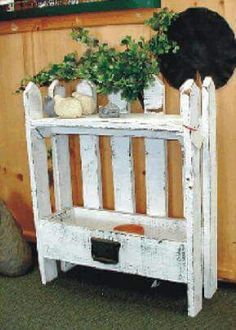 a white wooden shelf with potted plants on top and a black hat above it