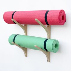 two yoga mats are hanging on the wall next to each other, one pink and one green