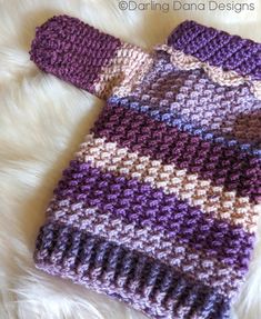 a purple and white knitted sweater laying on top of a furnishing area