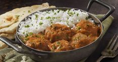 a bowl filled with rice and meatballs on top of a table next to bread