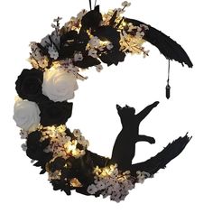 a wreath with white flowers and black cat silhouettes hanging from it's side