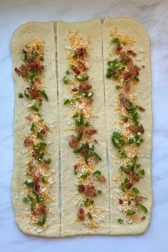 four flat breads with bacon, cheese and green onions on them sitting on a white surface