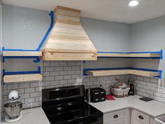 a stove top oven sitting inside of a kitchen next to a wall mounted range hood