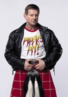 a man in a kilt and leather jacket with his hands on his hips looking at the camera