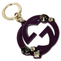 a close up of a key chain on a white background with a purple and gold logo