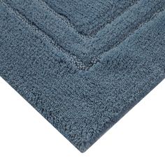 a blue bathroom rug on top of a white floor with an area rug in the middle