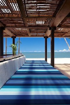 an outdoor dining area with blue and white table cloths on the floor, overlooking the ocean