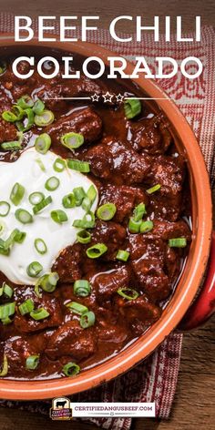 beef chili in a bowl with sour cream on top and green onions around the edges