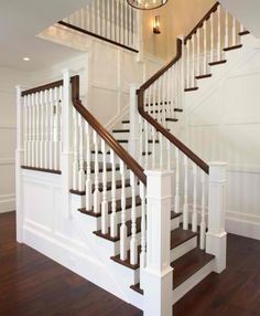 a white staircase with wooden handrails and wood flooring in a home setting