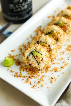 a white plate topped with sushi covered in toppings next to a bottle of wine