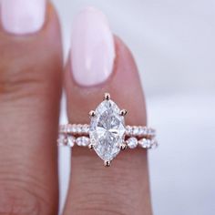 a woman's hand holding a ring with a diamond on the middle and side