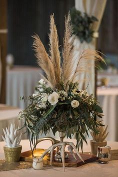 there is a vase with flowers and plants on the table