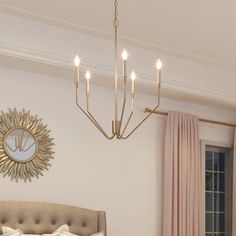 a chandelier hangs above a bed in a bedroom with pink drapes and curtains