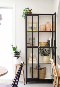 an open bookcase with plants and other items on it in a dining room area