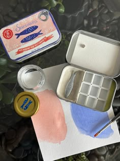 an assortment of crafting supplies sitting on top of a piece of paper with watercolor paint