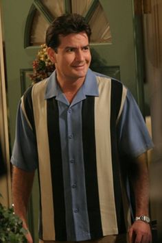 a man standing in front of a green door wearing a blue and black striped shirt