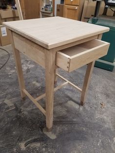 a wooden table sitting on top of a floor next to other woodworking tools and supplies