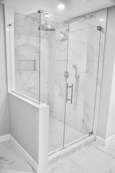 a walk in shower sitting next to a white tiled wall and floor with glass doors