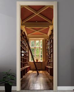 an open door leading to a library with bookshelves and a potted plant