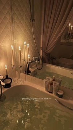 a bathtub filled with lots of candles next to a mirror