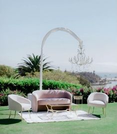 an outdoor wedding setup with chairs, couches and a chandelier in the background