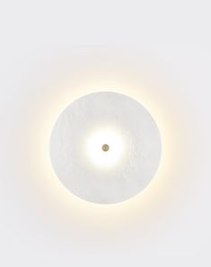 a round light fixture in the middle of a white wall with a circular light on it