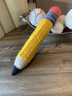 a crocheted corn on the cob is sitting in front of a plate with cupcakes